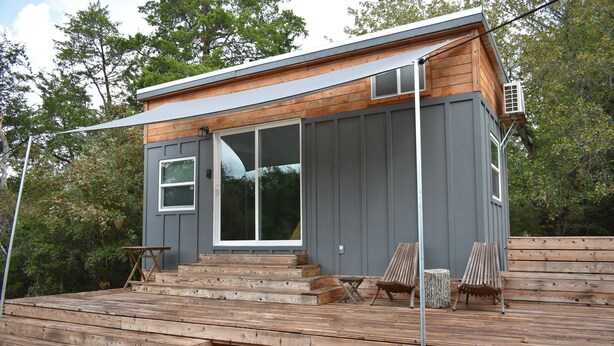 A small cabin with a wooden deck and two chairs. - Secluded Tiny Cabin with firepit, stargaze and hike (Paige)