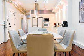 Una cocina moderna con electrodomésticos de acero inoxidable, una mesa de comedor con cuatro sillas y una lámpara colgante.