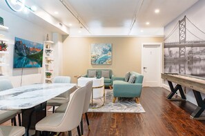 A modern interior with a dining area, a sofa set, and artwork on the walls. - Old City 2BR Apt w/ Shuffleboard! Walk Everywhere! (Philadelphia)