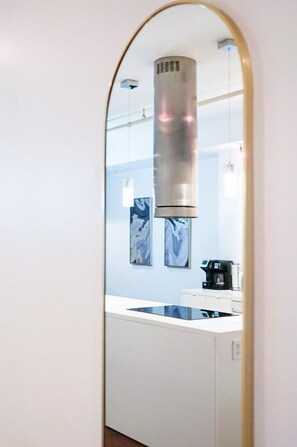 A modern kitchen with a stainless steel range hood, a white countertop, and a coffee machine. - Old City 2BR Apt w/ Shuffleboard! Walk Everywhere! (Philadelphia)