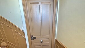 Een gang met een houten deur, een houten trap en een houten vloer.