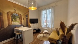 Een woonkamer met een bank, een salontafel, een televisie en een eethoek met krukken.