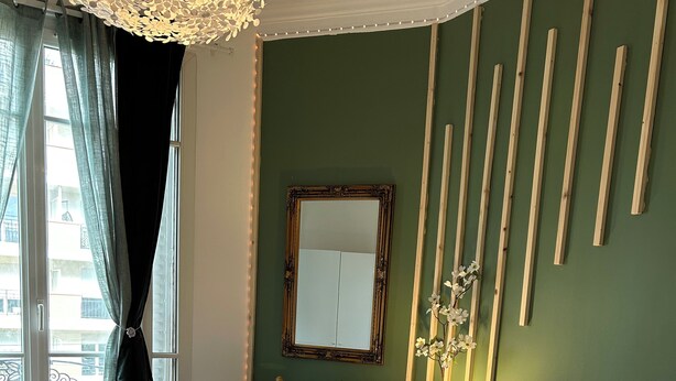 Een keurig opgemaakt slaapkamer met een bed, nachtkastje, dressoir en een spiegel aan de muur.