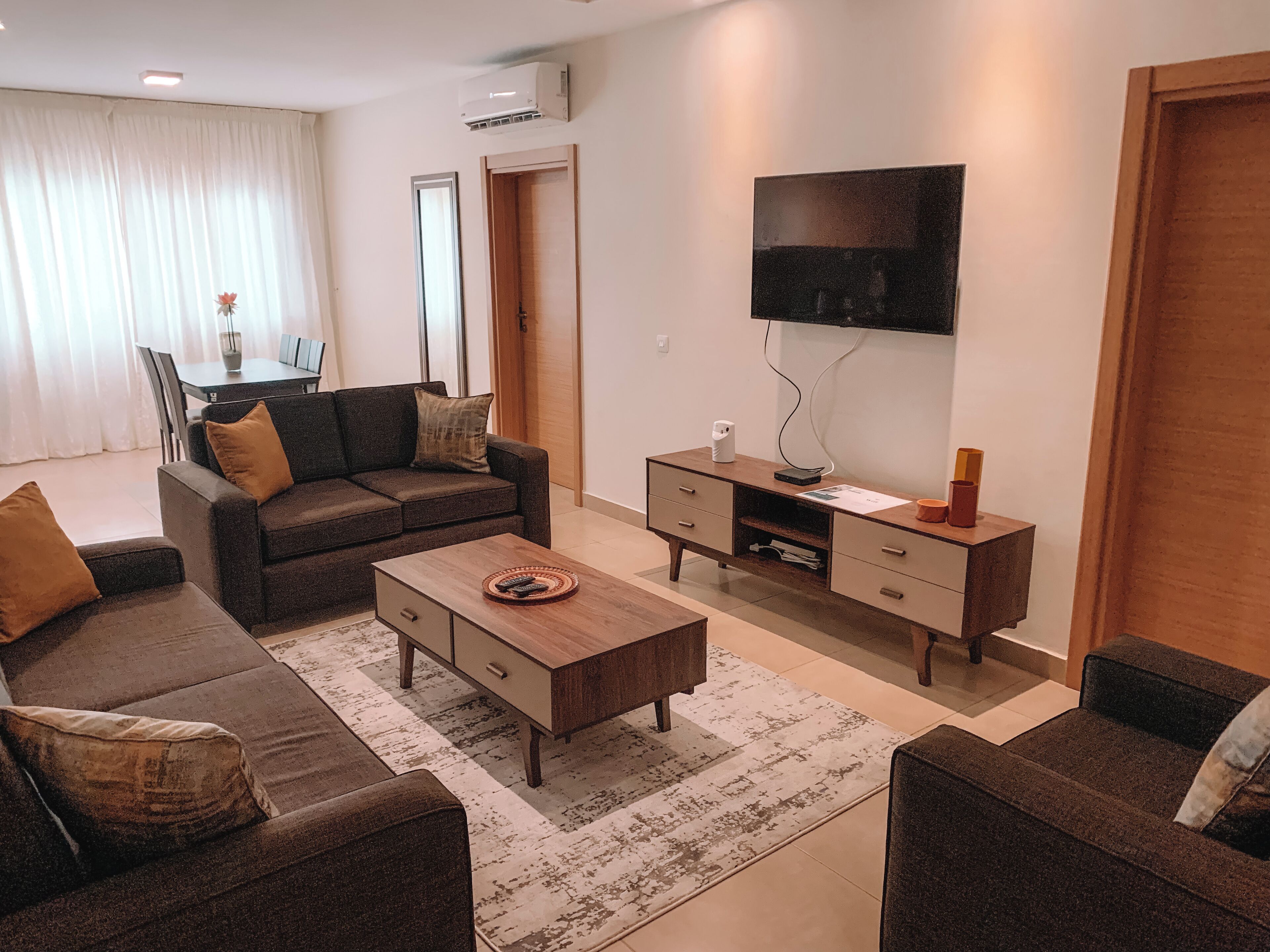 A modern living room with a sofa, coffee table, TV, and a wooden cabinet.