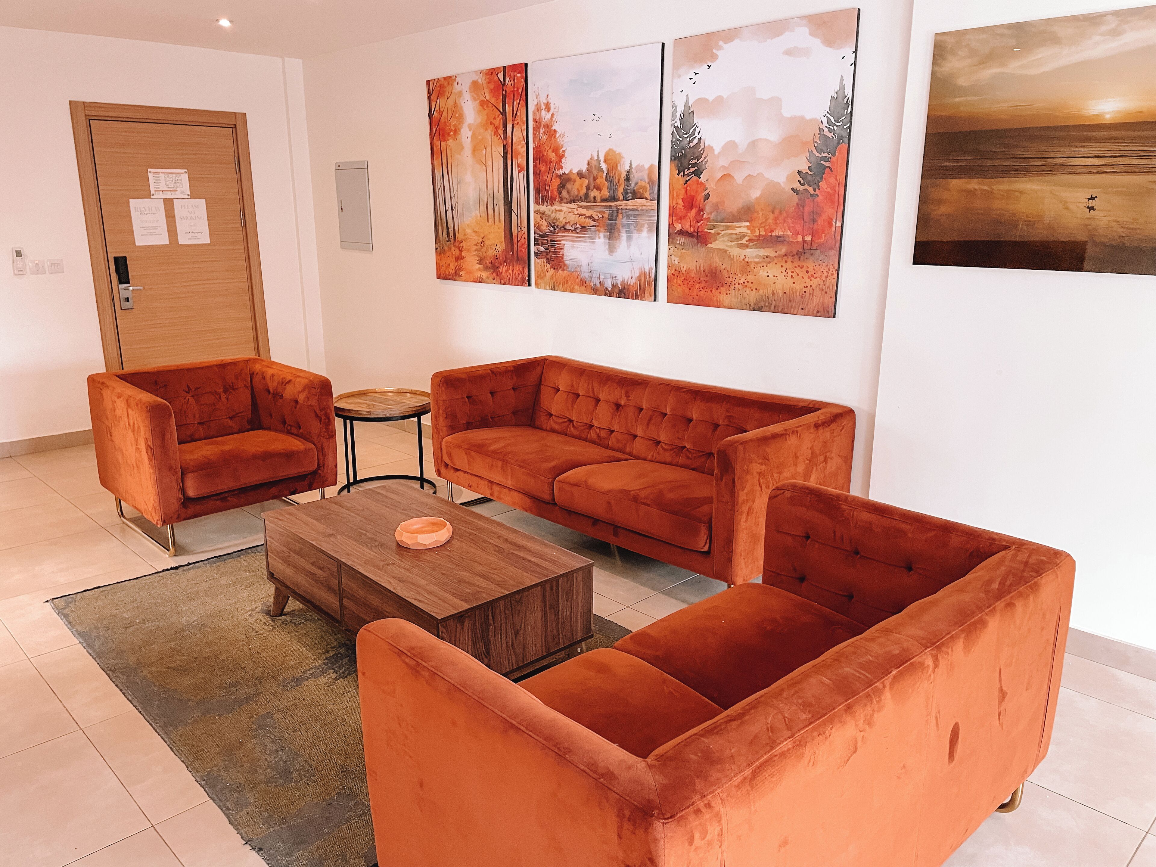 Een woonkamer met een zithoek, een salontafel en kunstwerken aan de muur.