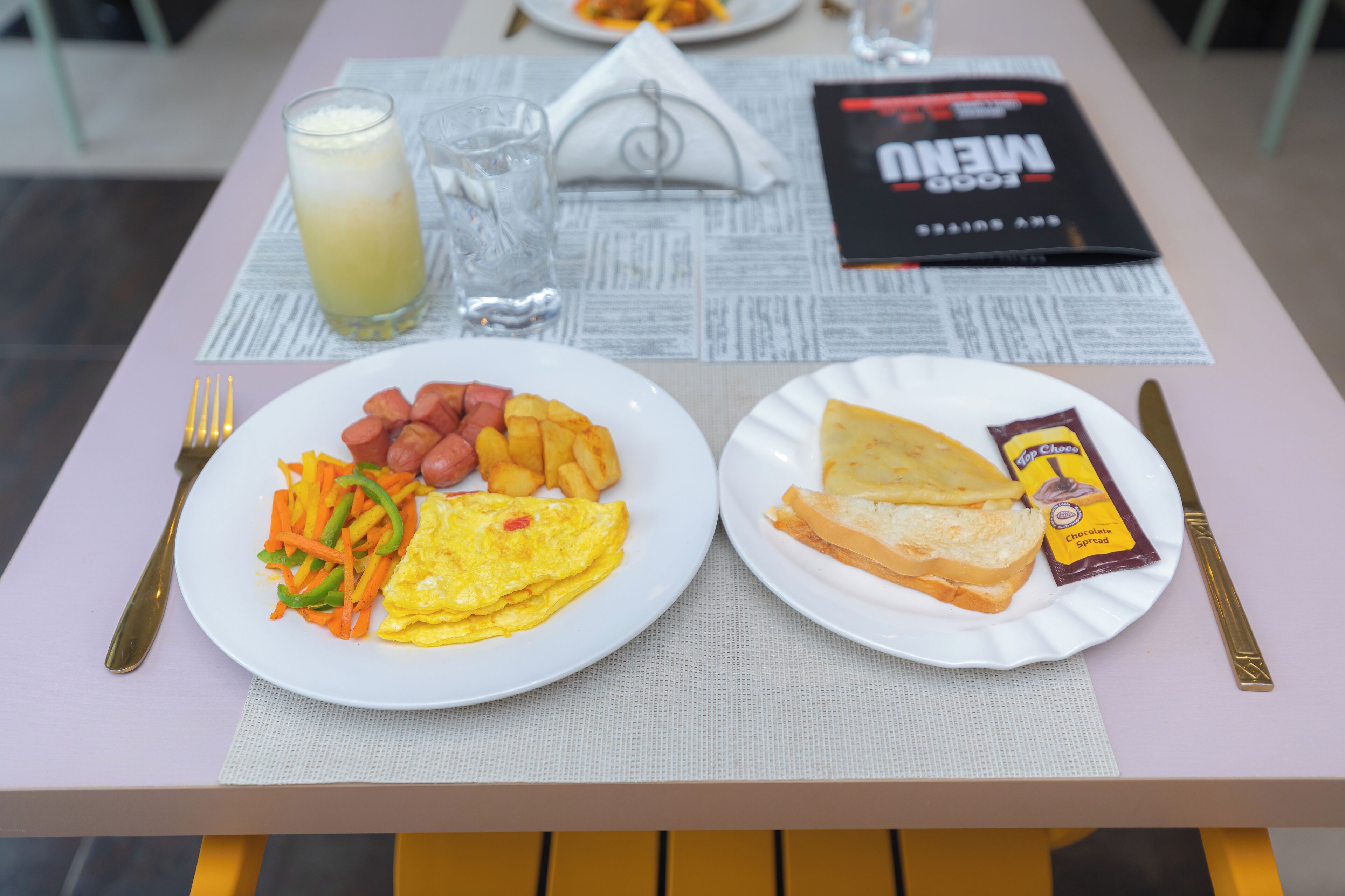 A table with two plates of food, a menu, and cutlery.