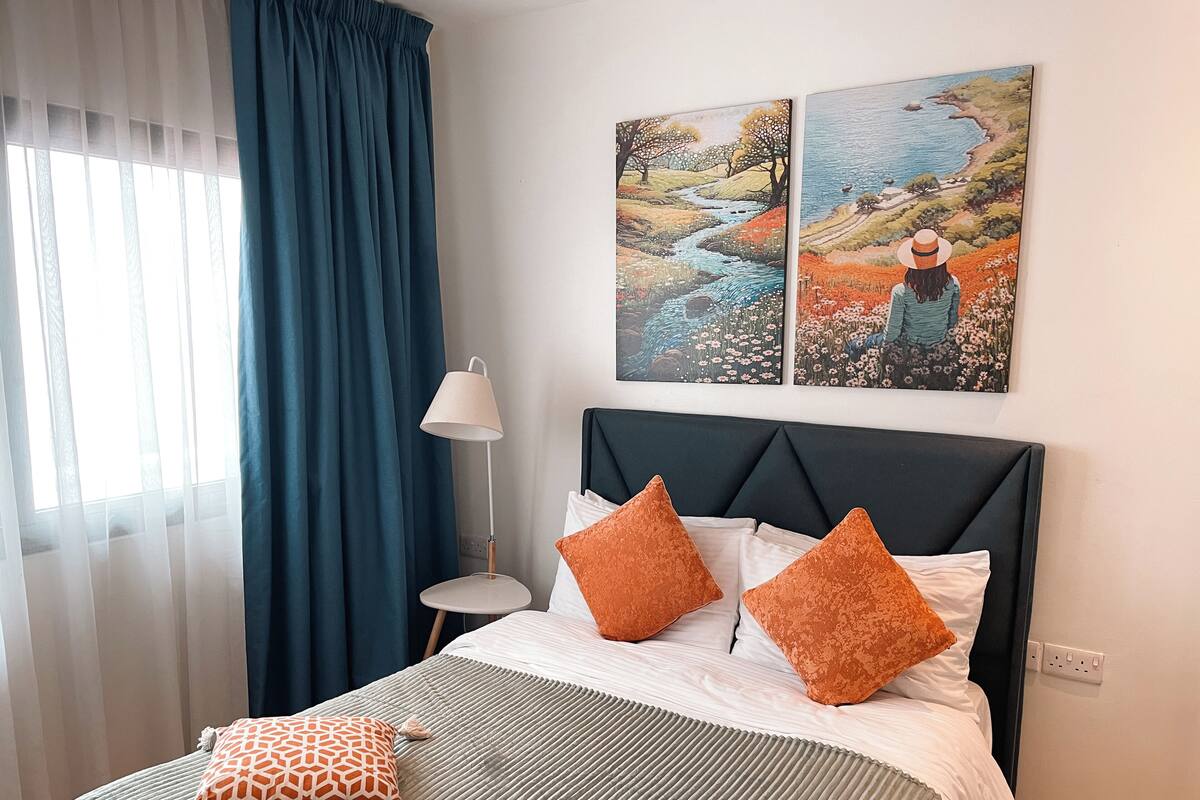 Une chambre d’hôtel avec un lit, une table de chevet, une lampe et deux tableaux au mur.
