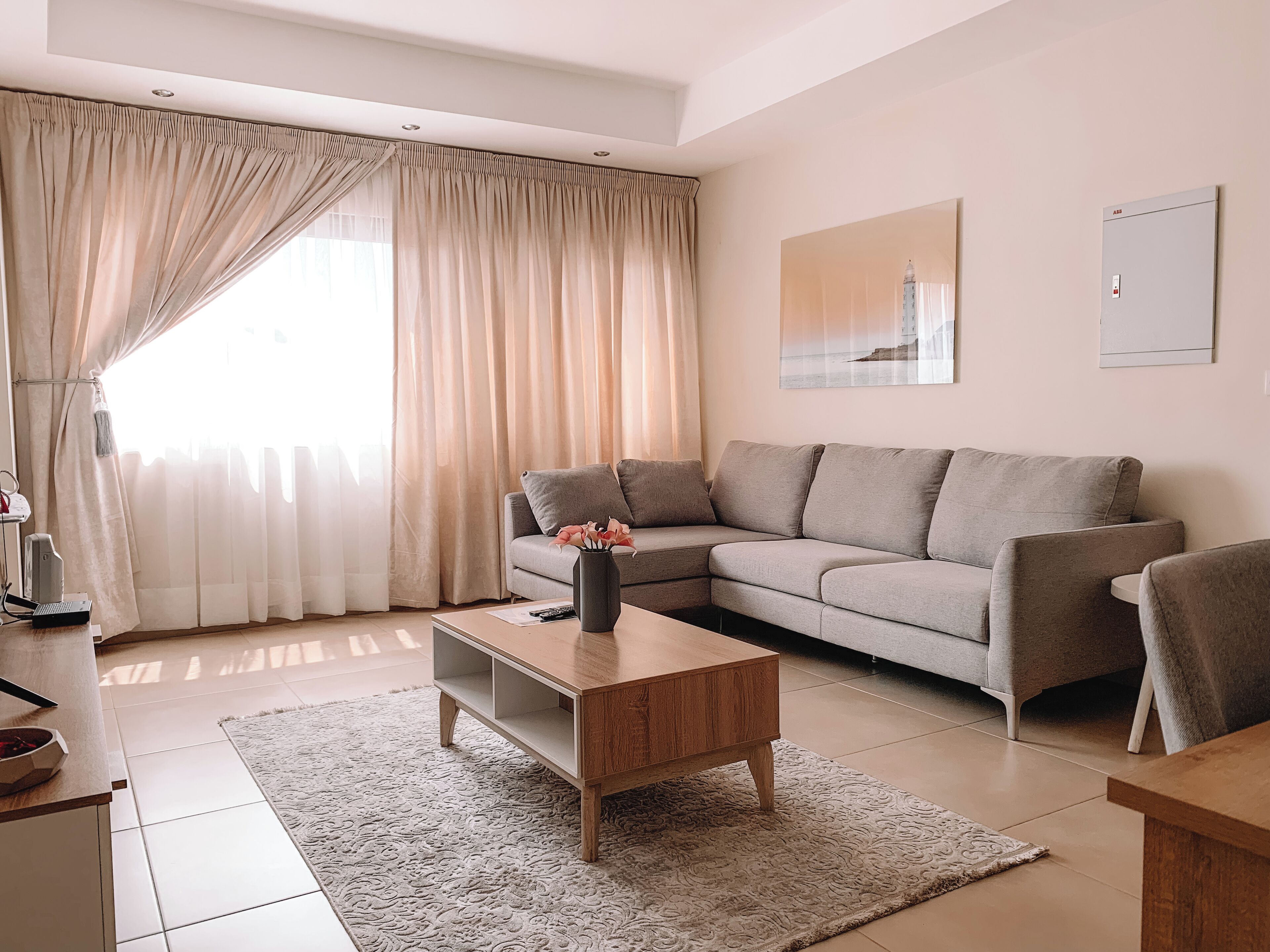 A modern living room with a sofa, coffee table, and a large window with curtains.