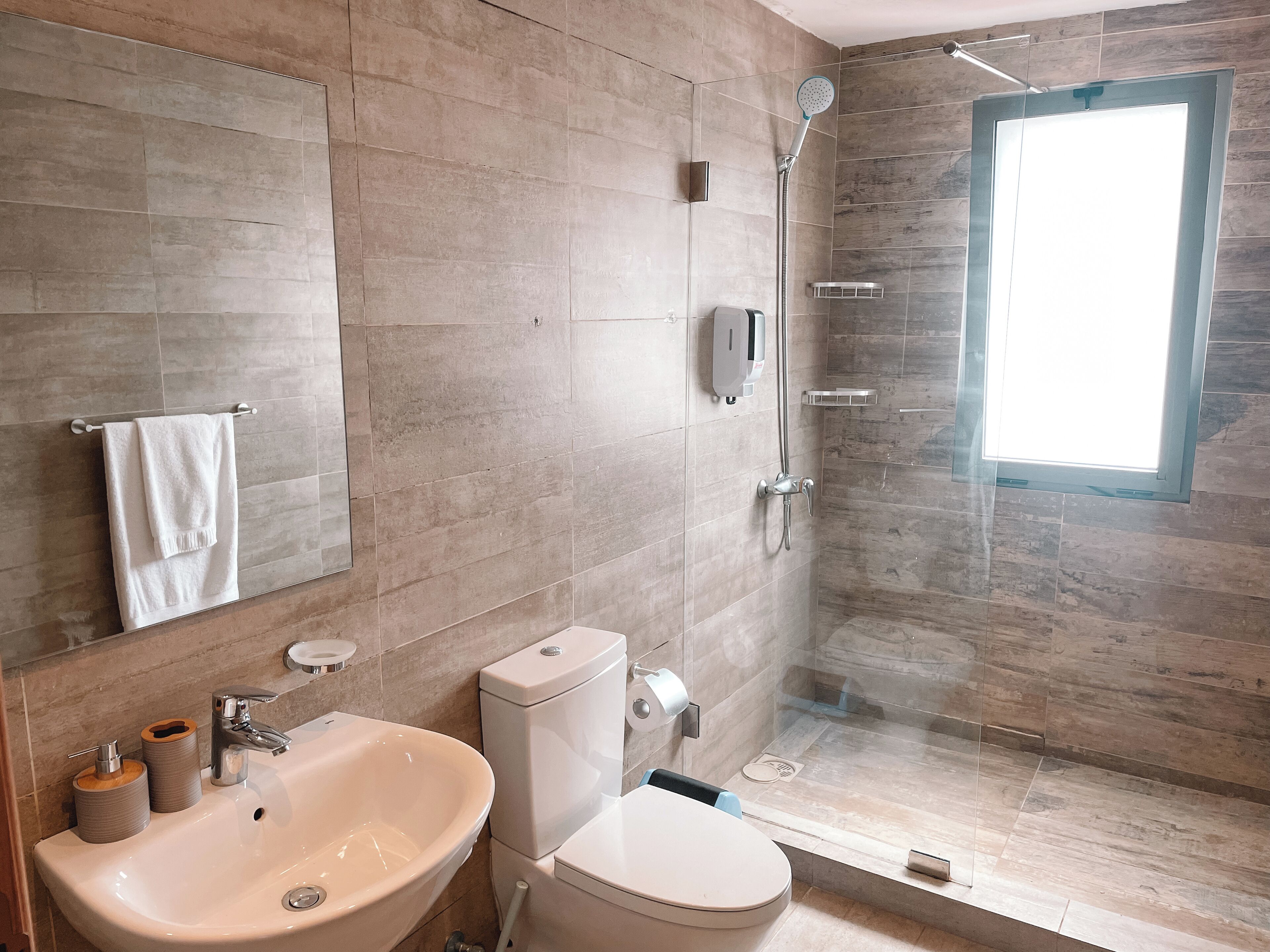 A modern bathroom with a large sink, toilet, and shower.