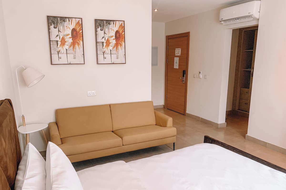 Une chambre d’hôtel avec un lit, un canapé et deux tableaux accrochés au mur.