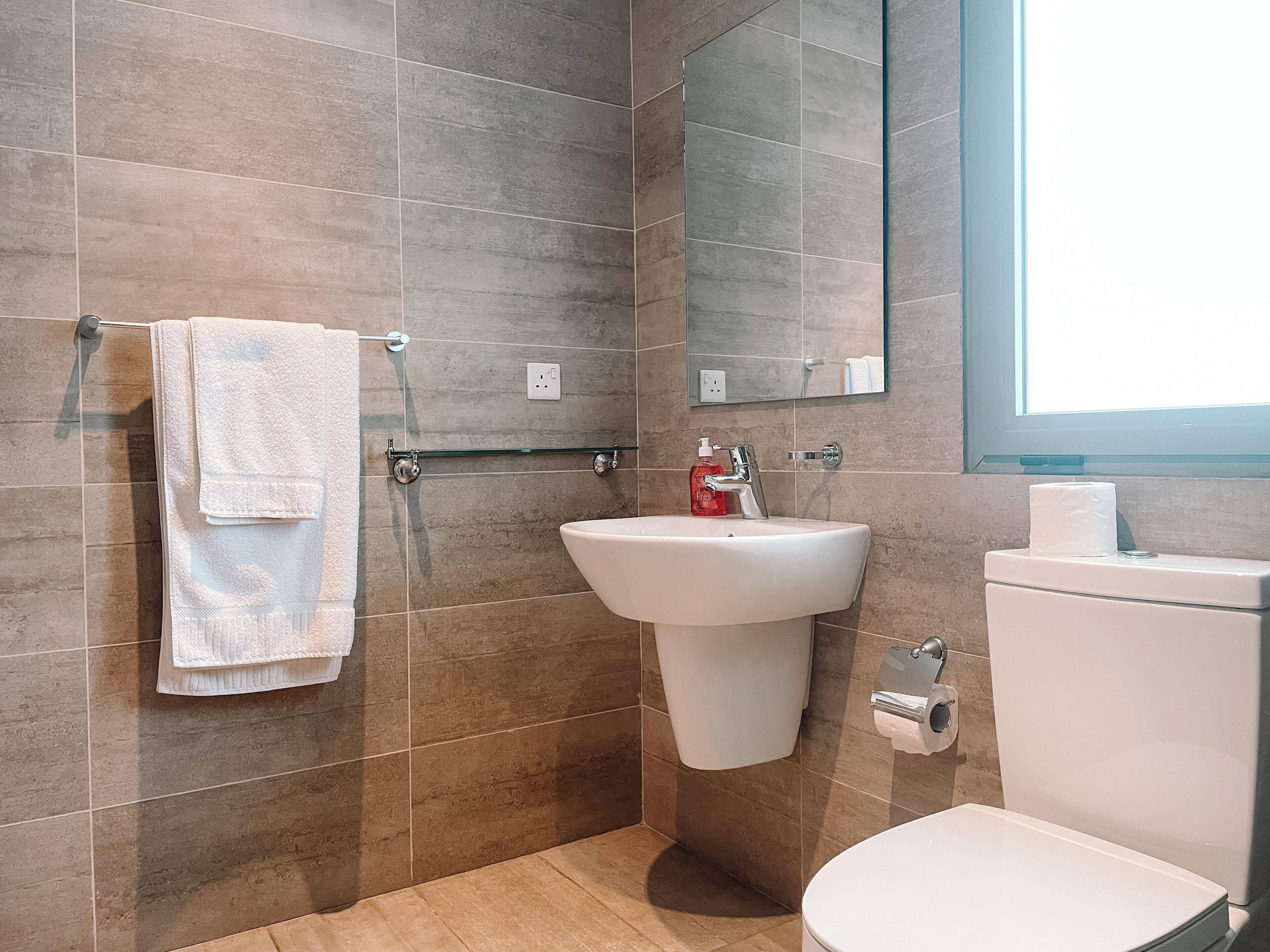 A bathroom with a sink, toilet, and towel rack.