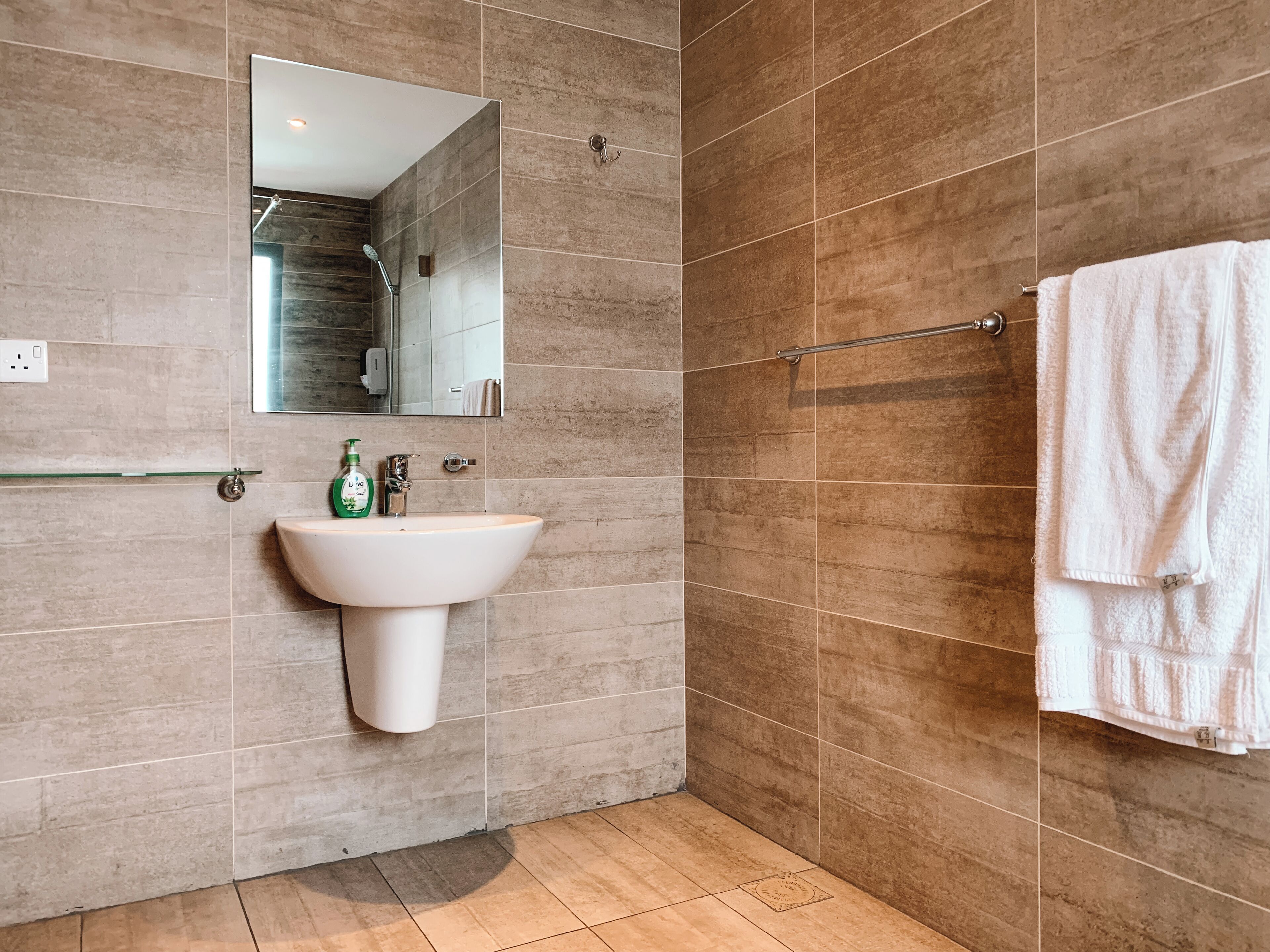 A modern bathroom with a pedestal sink, a mirror, and a towel rack.