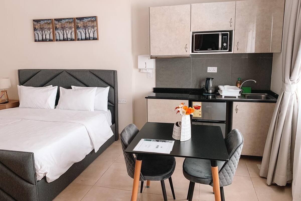 Une chambre d’hôtel comprenant un lit, un bureau avec deux chaises, un four à micro-ondes et une petite kitchenette.