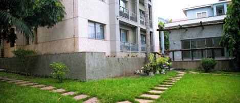 A courtyard with a grassy area, a concrete pathway, and a multi-story building with balconies.