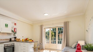 Una cocina moderna con armarios blancos, horno empotrado y comedor con mesa y sillas.