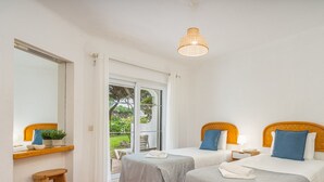 Habitación de hotel con dos camas, un ventanal grande y una lámpara colgante.