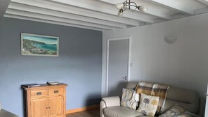 En stue med en beige sofa, et træskab og et billede på væggen.