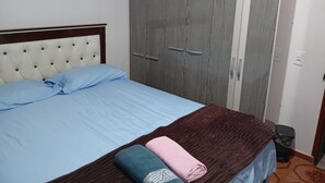 A bedroom with a bed, a wardrobe, and a small trash bin. - Beautiful and cozy house, spacious and close to the center (Boa Esperança Toledo)
