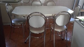 A kitchen with a white table, four chairs, a microwave, and a tiled backsplash. - Beautiful and cozy house, spacious and close to the center (Boa Esperança Toledo)