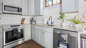 Una cucina moderna con mobili bianchi, forno in acciaio inossidabile, microonde, lavello e lavastoviglie.