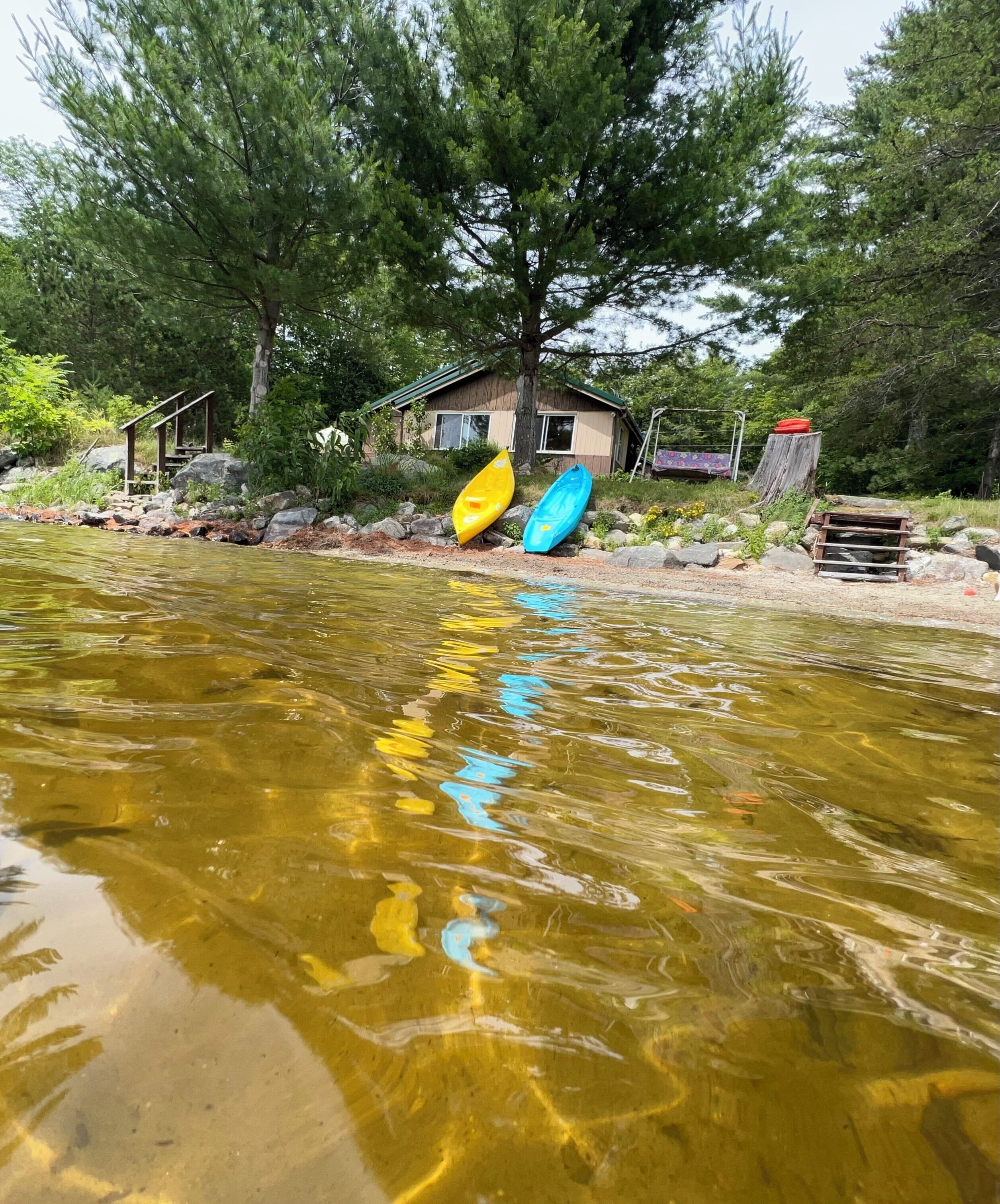 A river with kayaks and a house in the background.