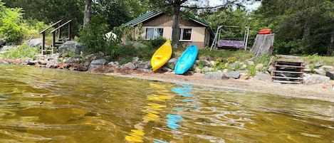 A river with kayaks and a house in the background.