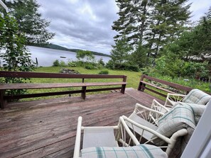 A wooden deck with wicker chairs and a bench overlooking a lake. - Beachfront Cottage Nestled in a Cove (Palermo)
