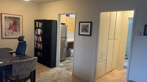 Un espace de vie compact comprenant un coin repas, une bibliothèque, un réfrigérateur et une porte donnant sur une autre pièce.