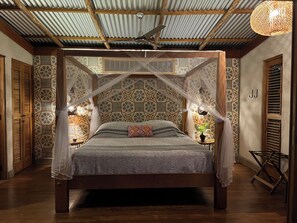 Ein Schlafzimmer mit Baldachinbett, strukturiertem Wandpapier und Deckenventilator.