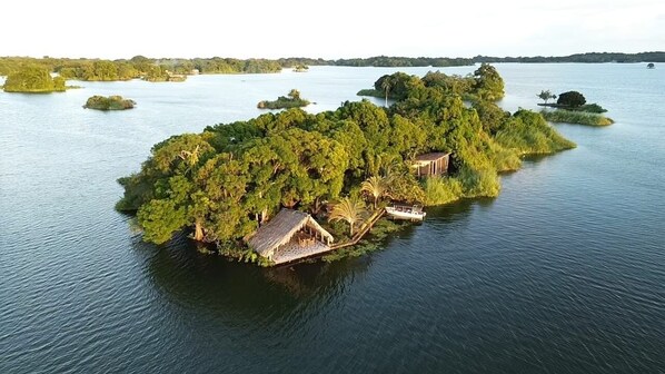 Eine Insel mit einem Gebäude mit Strohdach und einem Boot in der Nähe.