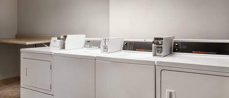 A laundry area with a bench, a washing machine, and a dryer.
