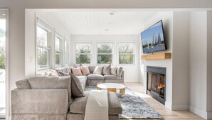 Una sala de estar moderna con chimenea, ventanas amplias y televisor.