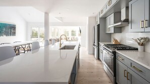 Una cocina moderna con una isla grande, electrodomésticos de acero inoxidable y suelo de madera clara.