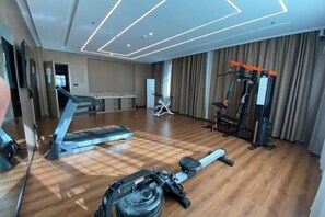 A spacious room with a wooden floor, a treadmill, a stationary bike, and a weight machine.