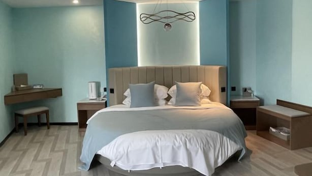 Ein modernes Hotelzimmer mit einem großen Bett, Nachttischen, einem Schreibtisch und einer ungewöhnlichen Wandleuchte.