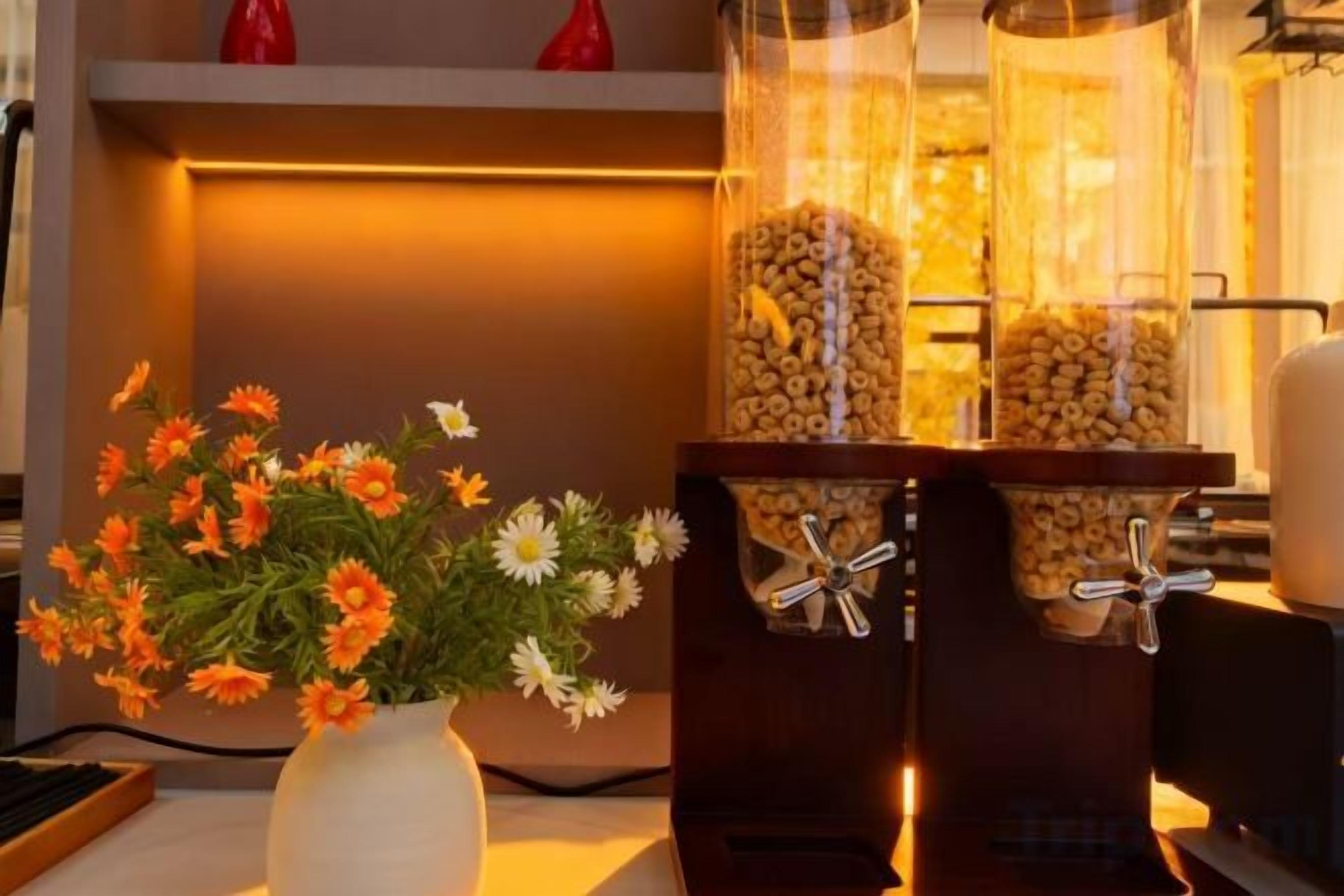 Ett rum med en vas med blommor, en popcornmaskin och en hylla med röda vaser.