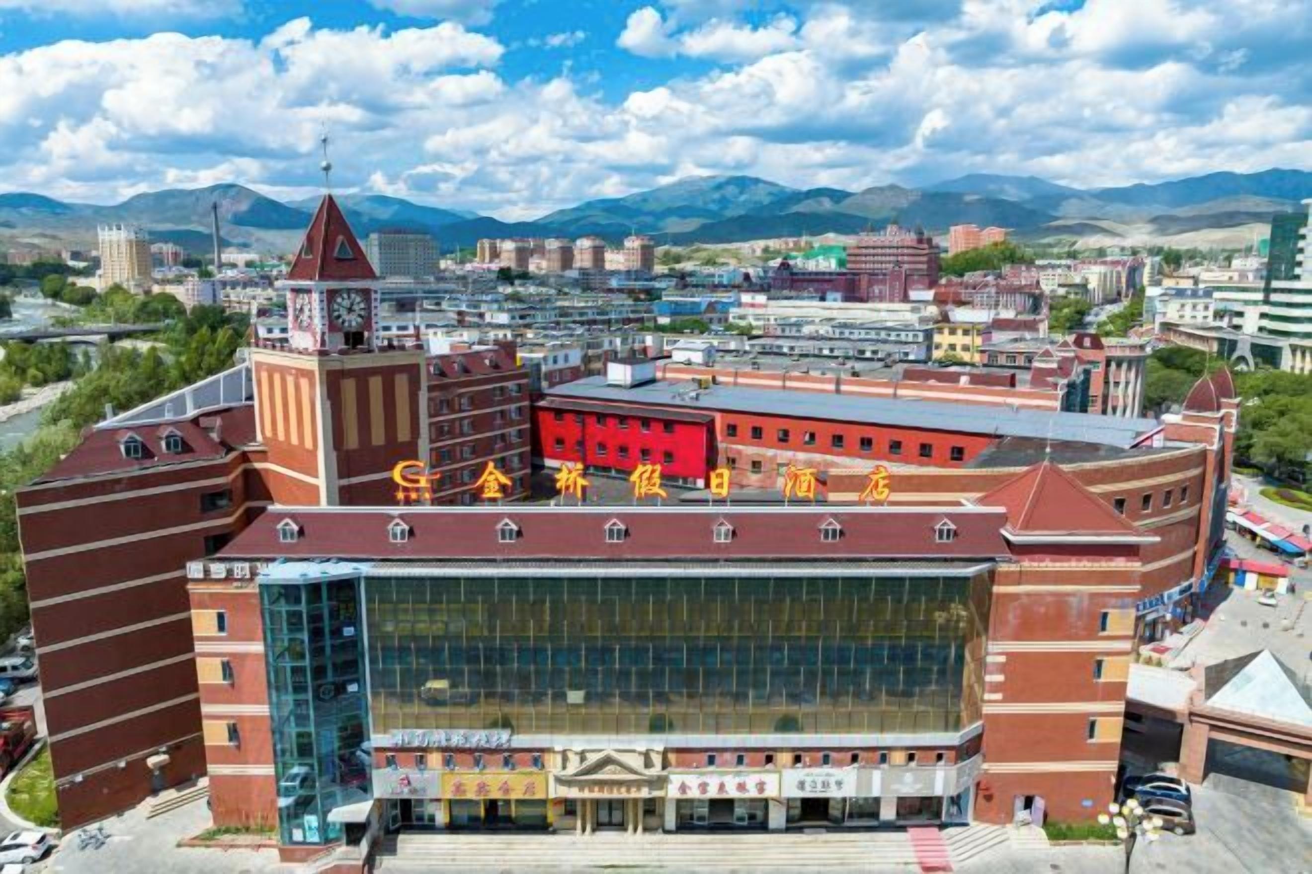 A large, multi-story building with a prominent clock tower, a glass facade, and a red roof.
