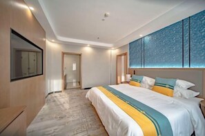 Quarto de hotel moderno com uma cama grande, televisão fixada na parede e chão estampado.