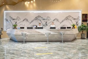 A reception desk with a marble countertop, two bar stools, and a backdrop of a mountain landscape. - Holiday Inn Altay Golden Bridge (Altay City)
