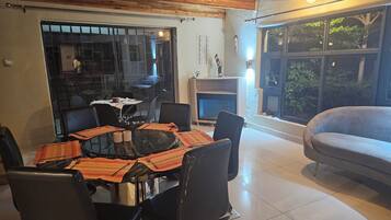 Un comedor con mesa de vidrio, sillas negras y chimenea.