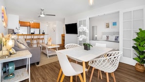 Una sala de estar moderna con comedor, muebles blancos y un ventilador de techo.
