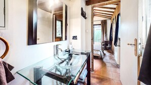 Un baño con un lavabo de cristal, vigas de madera y un espejo.