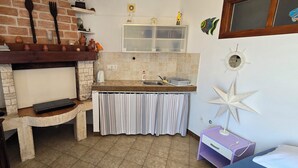 Una cucina con parete in mattoni, mensole in legno, un fornello e una finestra con tende.