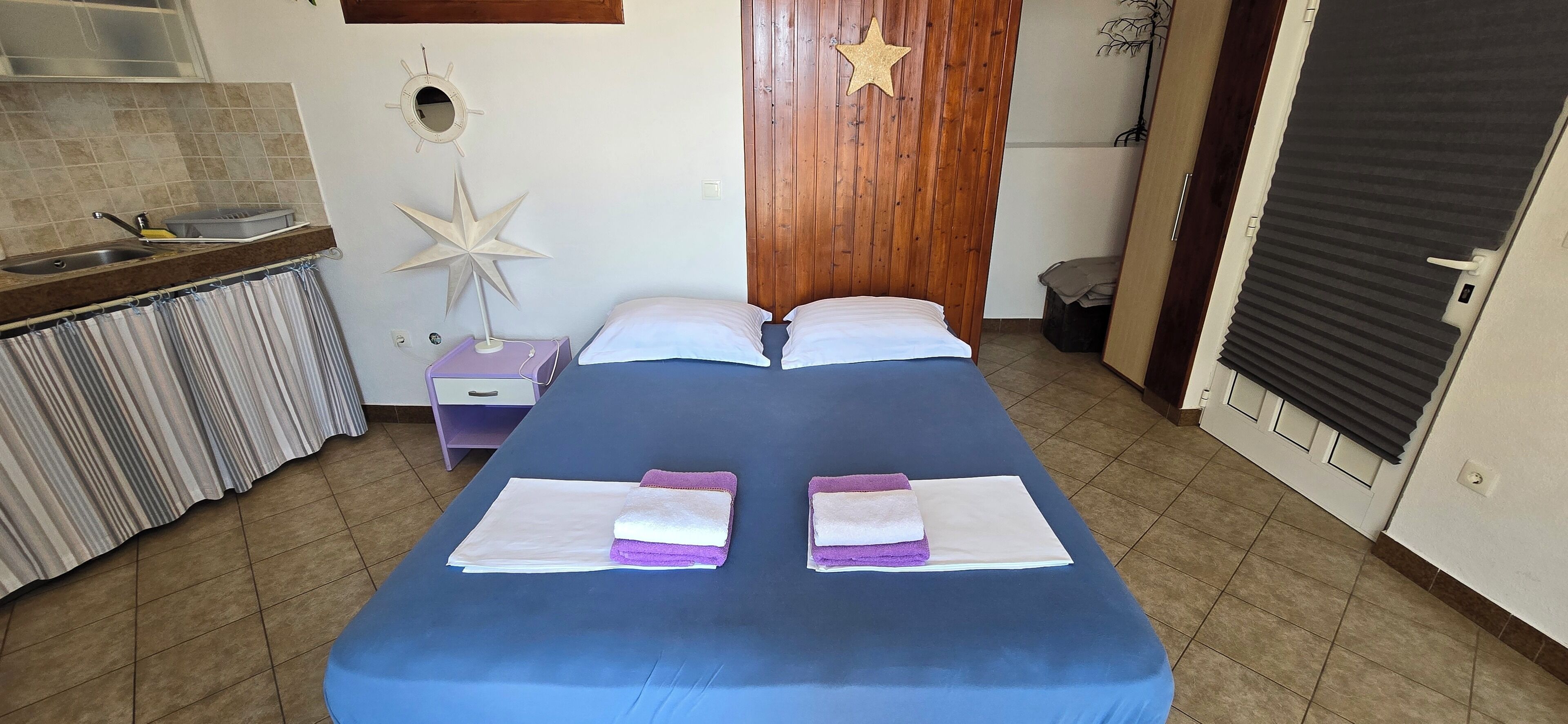 A bedroom with a bed, a nightstand, a star decoration, a wooden door, and a window.