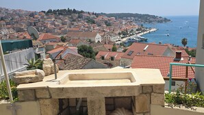 Paesaggio costiero con edifici a tetti in terracotta, un porto turistico e vista chiara sul mare.