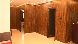 A hallway with wooden paneling, a red chair, and a door. - Abhivadya Gange  (Varanasi)