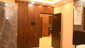 A modern hotel room with a wooden panel wall, a marble accent wall, and a large mirror. - Abhivadya Gange  (Varanasi)
