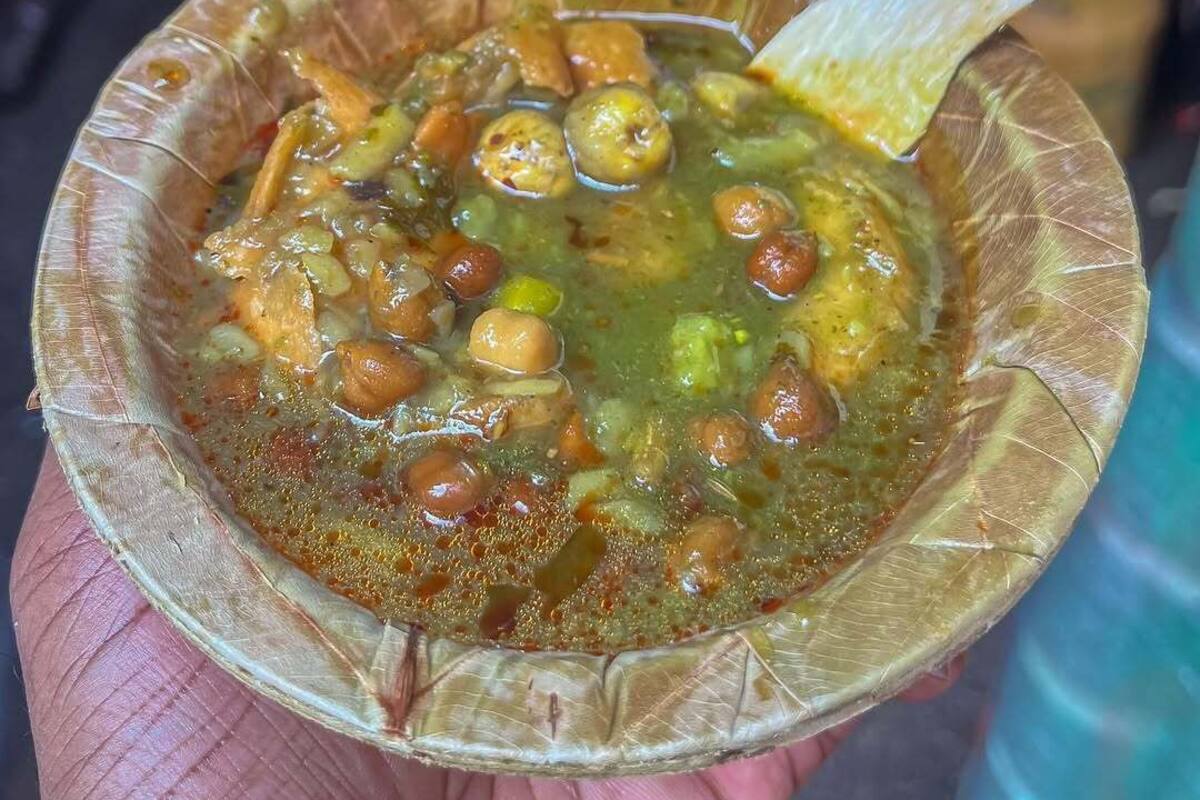 Un tazón de sopa con una cuchara, sostenido en una mano.