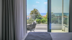 Un balcon avec vue sur la mer et les bâtiments, une chaise et un lit.
