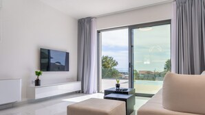 Un salon moderne doté d’un téléviseur à écran plat, d’un canapé, d’une table basse et d’une porte-fenêtre coulissante donnant sur un balcon.